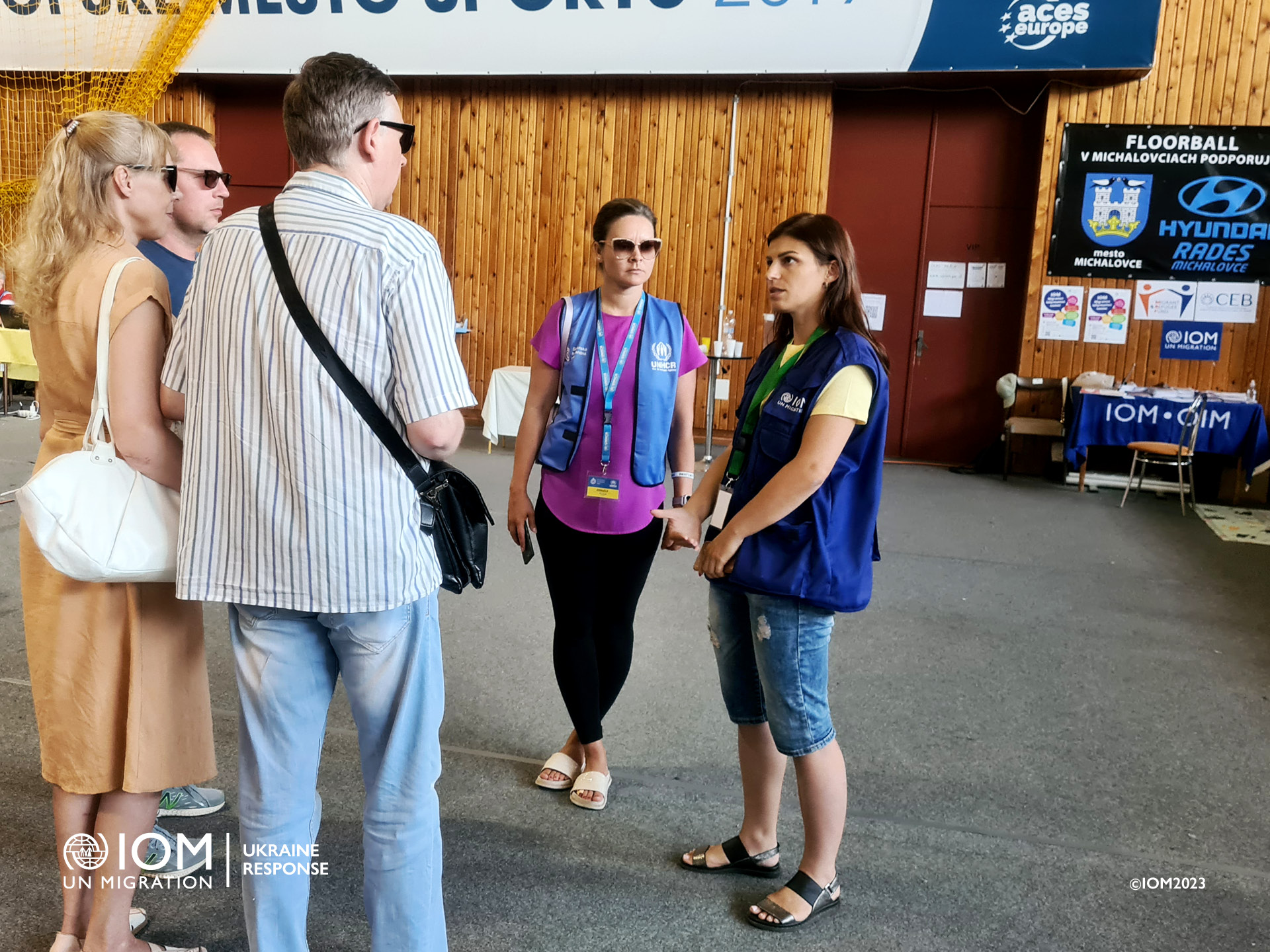 IOM frontline worker advising people with visual impairment from Ukraine and their assistant about necessary travel information. Photo © International Organization for Migration (IOM) 2023.